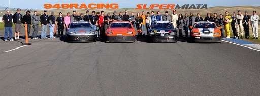 Race drivers with customized Miata cars at start line.