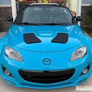 Blue Mazda sports car parked outside.