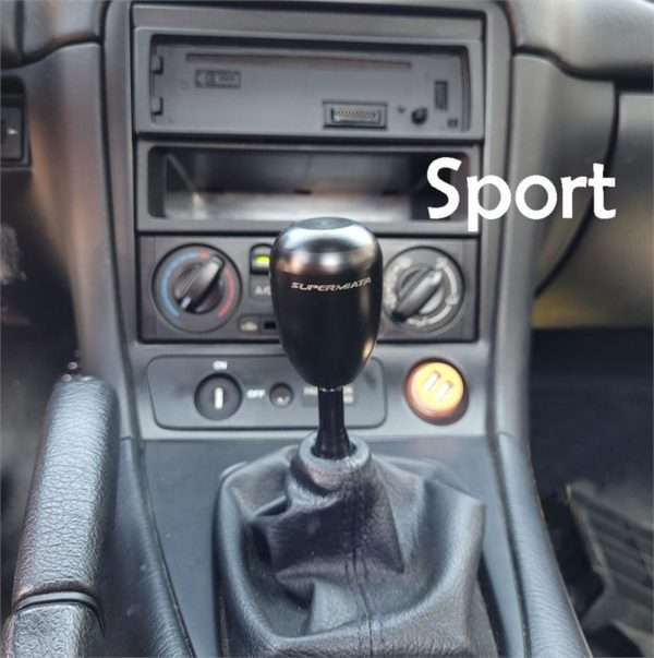 Car's manual gear shift and dashboard with "Sport" label.